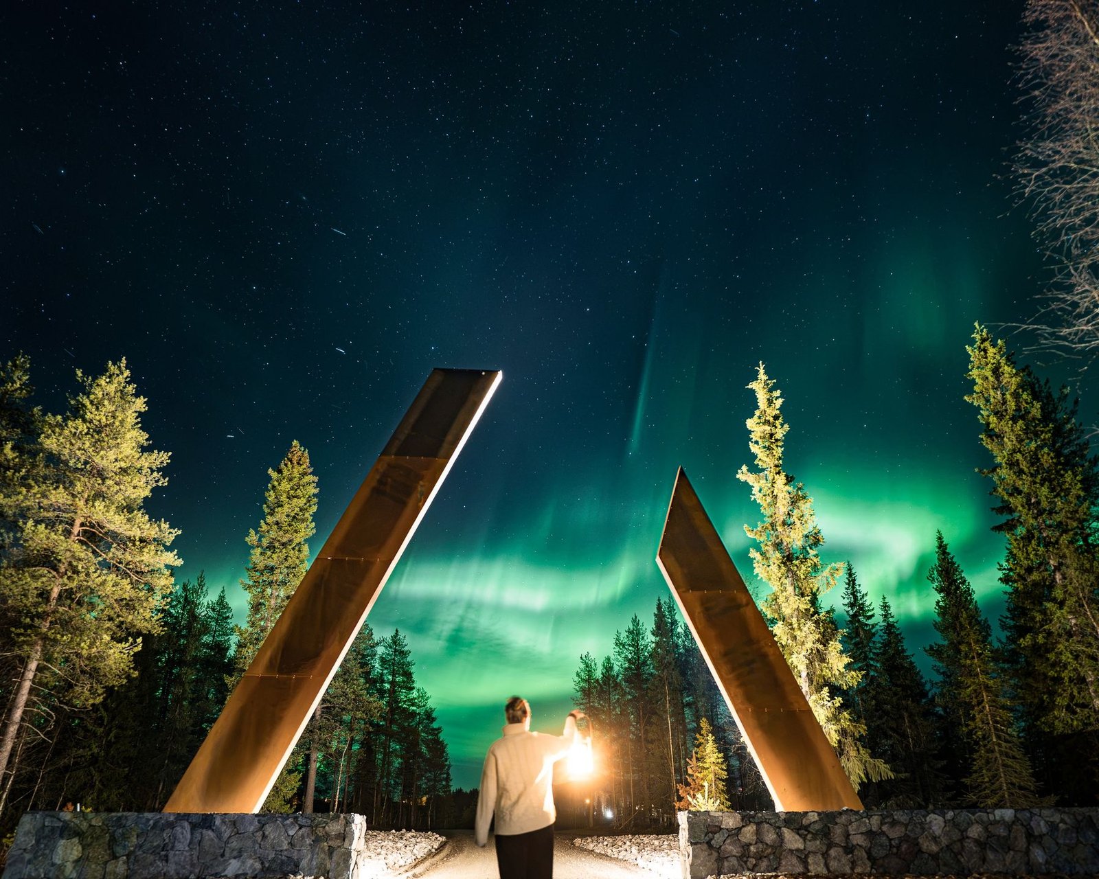 Northern lights over a forest gate with a lantern in Lapland