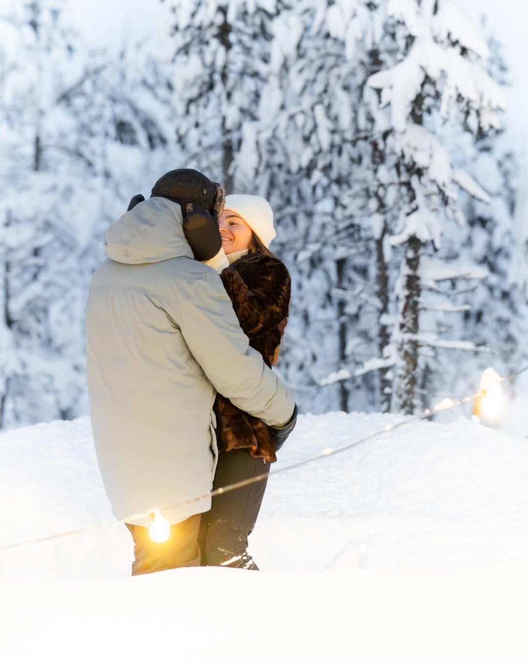 Couple photographed in a snowy forest with string lights in Lapland